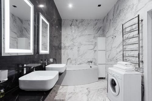 a bathroom with a tub sink and a washing machine at Odesa Pearl Apartments in Odesa