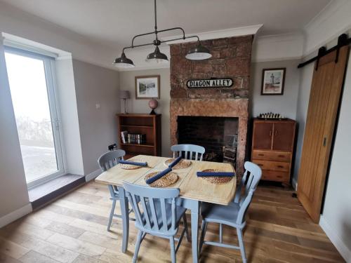 a dining room with a table and chairs and a fireplace at Welcoming 2 bedroom home with large outdoor space in Aspatria