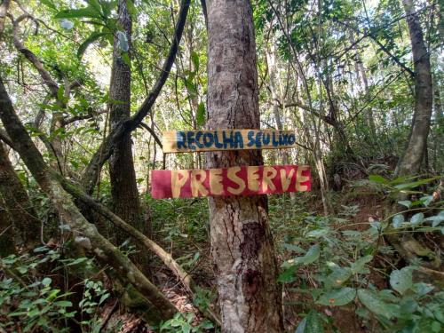 a sign on a tree in the woods at Chalé aconchegante, pertinho da cidade e conectada a natureza in Brasilia