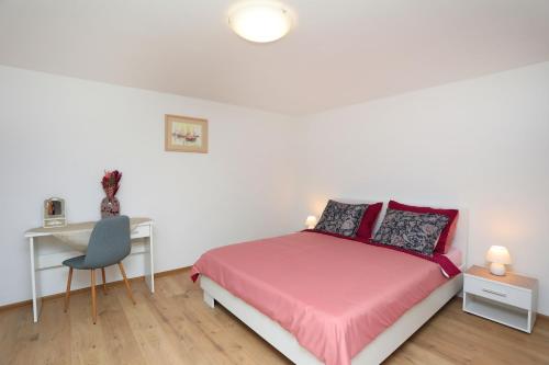 Biała sypialnia z różowym łóżkiem i biurkiem w obiekcie Holiday house Nono w mieście Labin