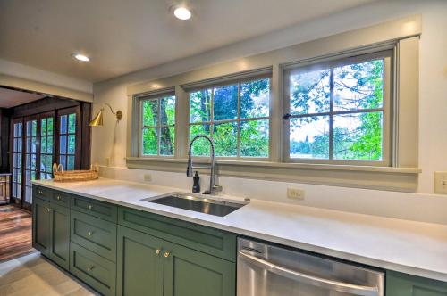 una cocina con armarios verdes, fregadero y ventanas en Peaceful and Elegant Cottage with Riverside View, en Oregon City