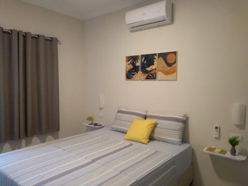 a bedroom with a large bed with a yellow pillow at Casa Temporada - São Jose in São José da Coroa Grande