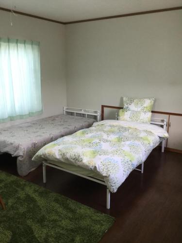 a bedroom with two beds and a window at Guesthouse Yui in Hongu