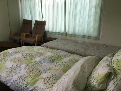a bedroom with a bed and two chairs and a window at Guesthouse Yui in Hongu