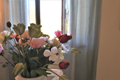 a vase filled with flowers in front of a window at CLAUDIA VACANZA TOSCANA - Appartamento Nocciolo- 10 min da Siena in Malignano