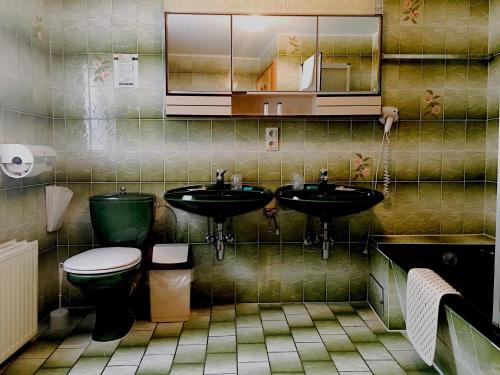 a bathroom with two sinks and a toilet at Bed & Breakfast du Château in Vianden