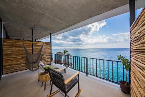 um quarto com uma varanda com uma rede de descanso e o oceano em Hotel B Unique em Cozumel