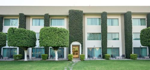 un edificio con plantas a su lado en Hotel Estancia Business Class, en Guadalajara