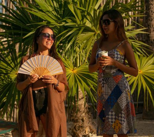 two women standing next to each other holding a fan at El Regalo El Cuyo in El Cuyo