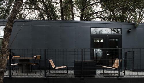 a black house with chairs and a table and a tree at AutoCamp Catskills in Saugerties
