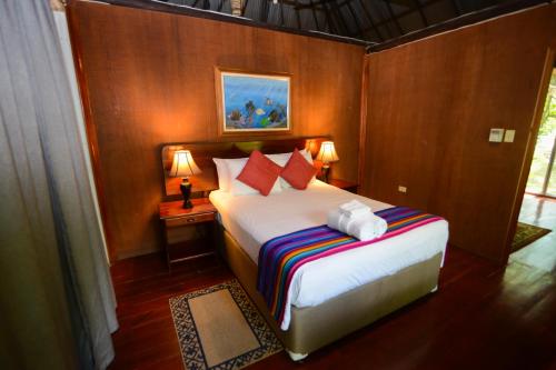 a bedroom with a bed and two tables with lamps at KikiWitz Resort in Belmopan