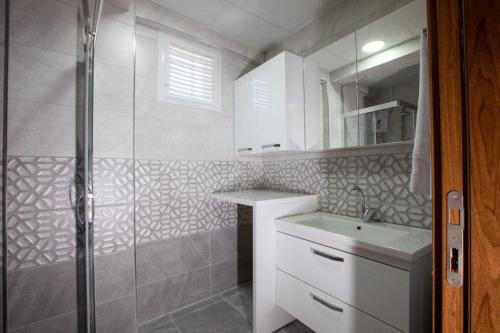 ein weißes Bad mit einem Waschbecken und einer Dusche in der Unterkunft BRAGEÇAM REZİDANS OTEL in Konak