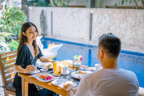 Un hombre y una mujer sentados en una mesa comiendo comida en Jani's Place Cottage by Purely, en Ubud