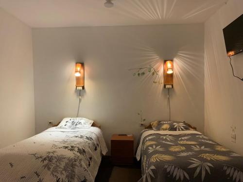a bedroom with two beds and two lights on the wall at Tiyana House in Cusco