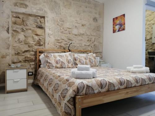a bedroom with a bed with a stone wall at Il Daviduccio ibla in Ragusa