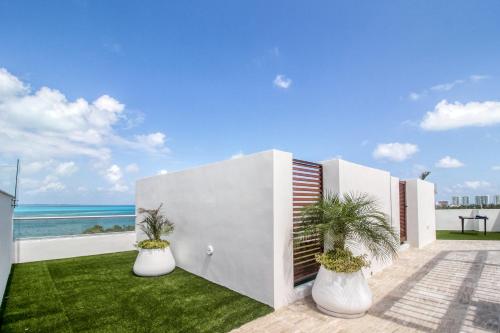 una casa blanca con dos plantas en jarrones blancos en Confort Place Takh 403 Studio, en Cancún