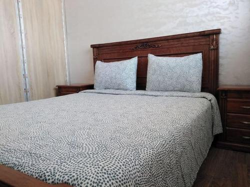 - une chambre avec un lit doté d'une tête de lit en bois et d'oreillers dans l'établissement Appartement bien situé Dahomey city . Bahia beach, à Bouznika