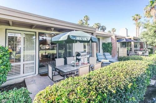 a patio with a table and chairs and an umbrella at Private Country Club Condo on awesome golf course! in Palm Desert
