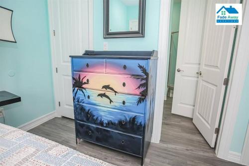 a blue dresser with a painting on it in a bedroom at Kalm by the Beach - Ocean View - Sleeps 14 in Freeport