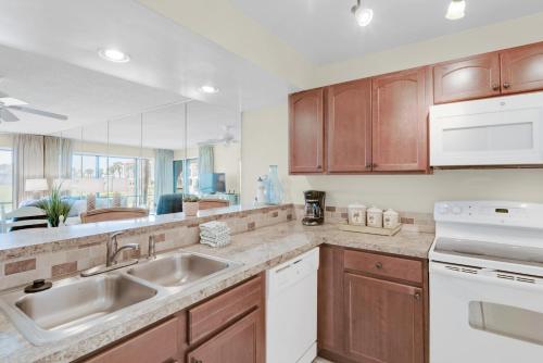 a kitchen with wooden cabinets and a sink at Edgewater Golf Villa 304 in Panama City Beach