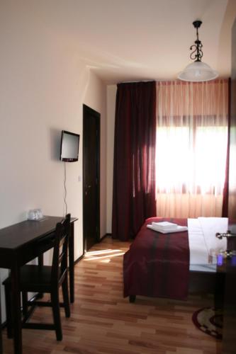 a bedroom with a bed and a desk and a window at Pensiunea Cristian Covasna in Covasna
