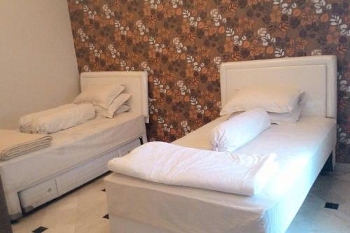 two beds in a room with white sheets and pillows at Nice house with modern furniture at Bandung in Bandung
