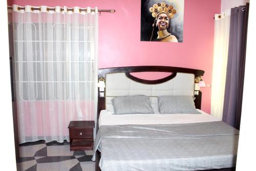 a bedroom with a bed with a pink wall at RESIDENCE PALAIS DU STADE in Cotonou