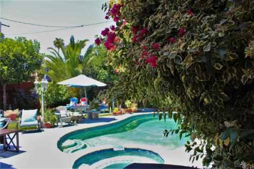 a swimming pool with flowers and chairs and an umbrella at Sweet Dreams B&B LA in Sherman Oaks