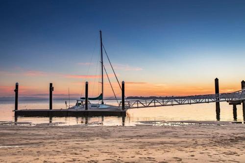 a sailboat is docked at a dock on the beach at LOVELY PET FRIENDLY SELF CONTAINED HOLIDAY VILLA in Bongaree