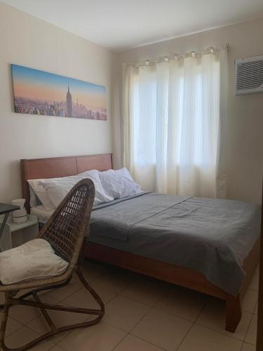 um quarto com uma cama, uma cadeira e uma janela em Downtown Davao City 2 BR Condo with pool and gym em Dávao