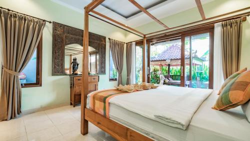 a bedroom with a bed and a large window at The Village Guest House in Ubud