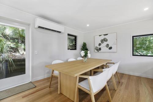 a dining room with a wooden table and white chairs at Duke St Convenience at your doorstep Beach living in the heart of the village close to cafes Ocean glimpse in Sunshine Beach