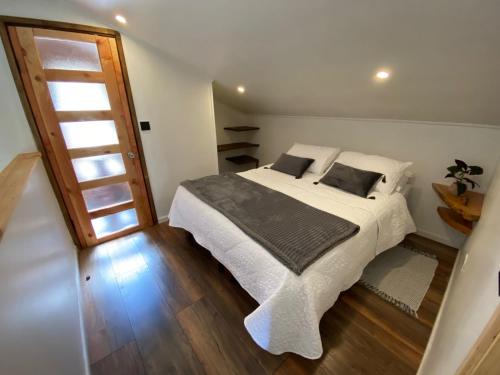 a bedroom with a large bed with white sheets and pillows at Cabaña con tinaja en bosque Valdiviano in Valdivia