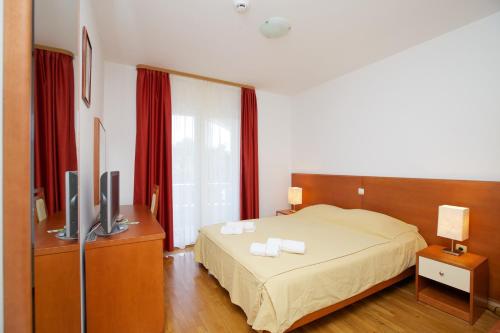 Schlafzimmer mit einem Bett, einem TV und roten Vorhängen in der Unterkunft Villa Daniela in Bol