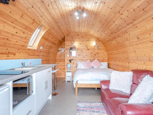 a bedroom in a wooden cabin with a bed and a couch at Ewe Two in Flint