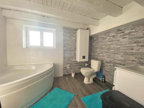 une salle de bain avec une baignoire blanche et des toilettes dans l'établissement Maison d'hôtes A la fontaine fleurie 88, à Frémifontaine
