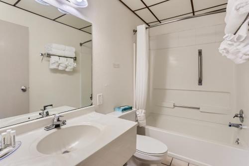 ein Badezimmer mit einem Waschbecken, einem WC und einem Spiegel in der Unterkunft Baymont by Wyndham Loveland - Fort Collins Area in Loveland