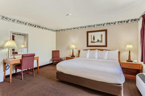 a hotel room with a bed and a desk at Baymont by Wyndham Loveland - Fort Collins Area in Loveland
