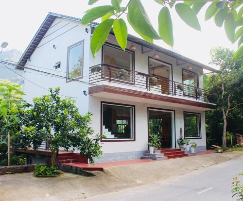 a white house with a tree in front of it at Ba Be Hostel in Bak Kan