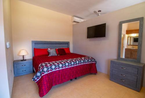 1 dormitorio con cama roja y TV en Hacienda Gallardos 104-1, en San Carlos