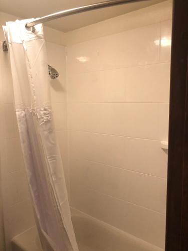 a shower with a white shower curtain in a bathroom at Red Lion Inn and Suites La Pine, Oregon in La Pine
