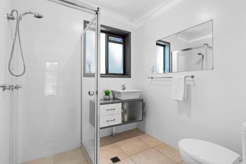 a white bathroom with a shower and a sink at Graebill 2 Bedroom 2 Bathroom Light and Spacious Duplex Walk to Beach Great Outdoor Entertaining Area in Sunshine Beach