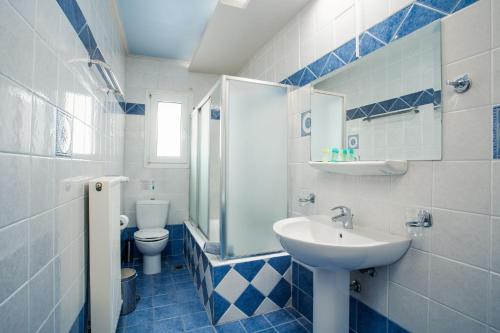 a blue and white bathroom with a sink and a toilet at Blue Sea Hotel in Mytilini