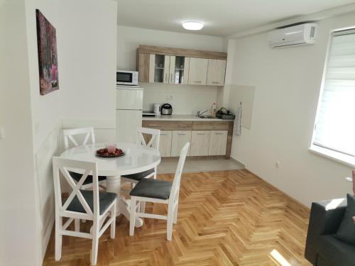 una cucina e una sala da pranzo con tavolo e sedie bianchi di JOKER Apartman a Požarevac