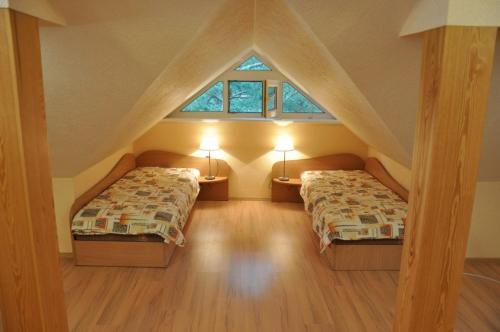 a attic bedroom with two beds and two windows at Vila Krantas in Palanga