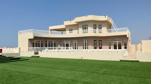 un grand bâtiment avec une pelouse devant lui dans l'établissement Ocean Chalet, à Salalah