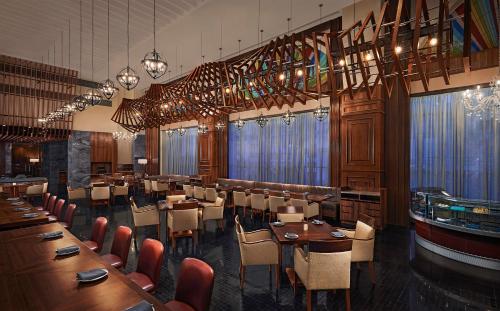 a restaurant with wooden tables and chairs and chandeliers at Hyatt Centric Janakpuri New Delhi in New Delhi