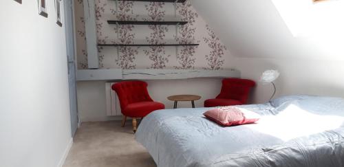 - une chambre avec un lit et deux chaises rouges dans l'établissement Triplex tout confort, plein centre ville Bauge en Anjou, à Baugé