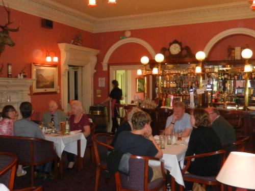 a group of people sitting at tables in a restaurant at Morangie Hotel Tain in Tain