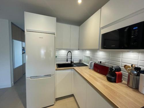 a kitchen with white cabinets and a white refrigerator at VUE SUR MER - Magnifique appartement tout confort - Terrasse et parking privé in Cagnes-sur-Mer